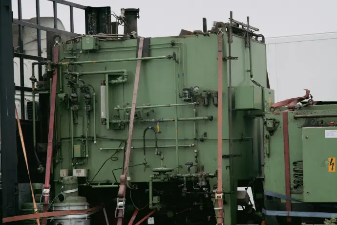 a large green machine sitting on top of a train track